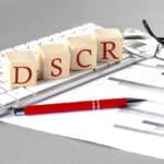 DSCR written on a wooden cube on the keyboard with chart on a grey background