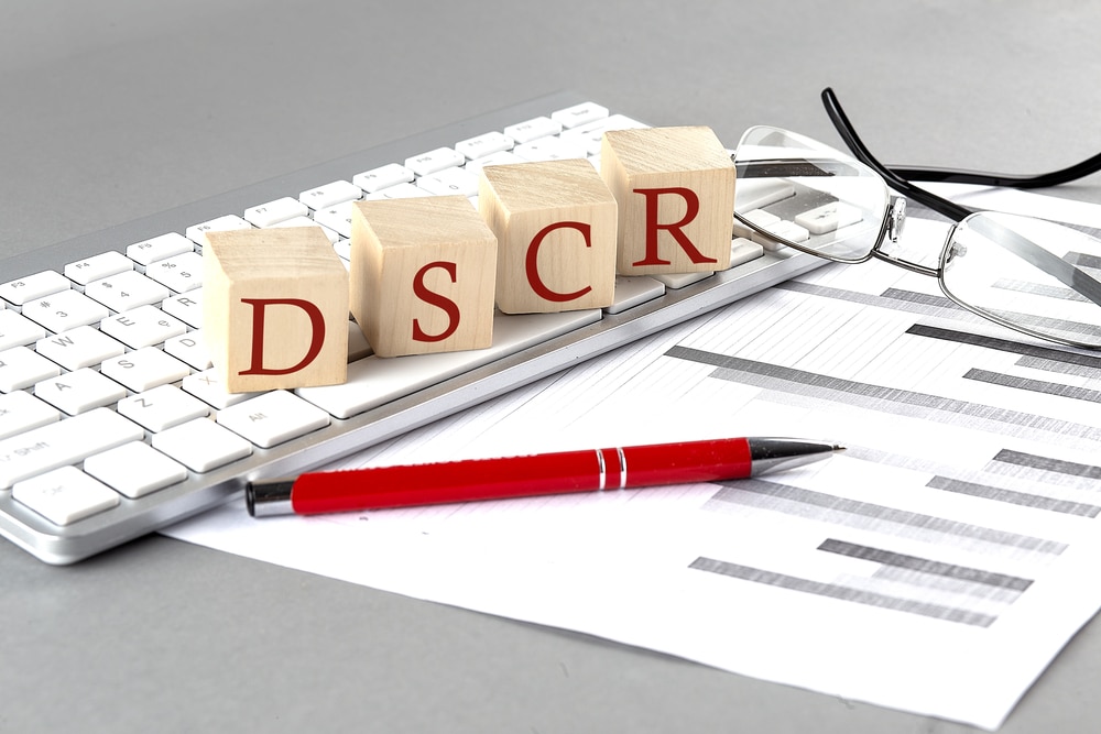 DSCR written on a wooden cube on the keyboard with chart on a grey background