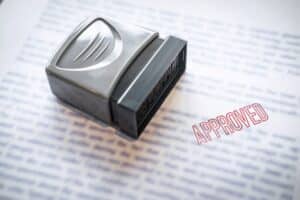 A rubber stamp marked "APPROVED" in red ink is placed on a document with printed text, highlighting the decision process in applications like Hard Money vs Traditional Loans.